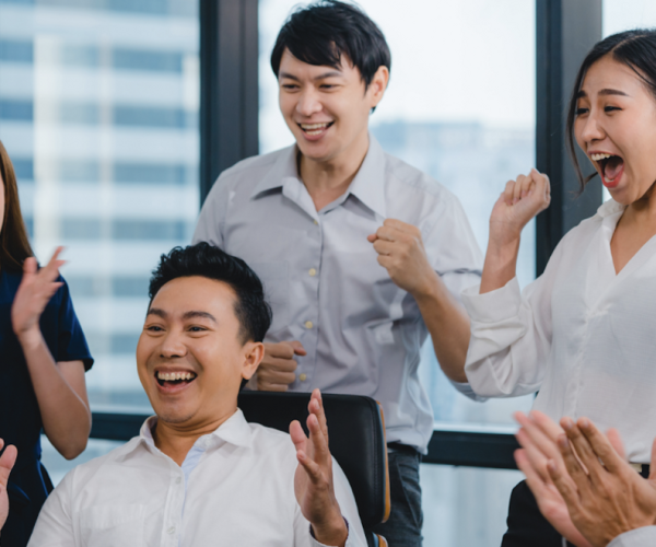 Millennial group of young Asian business people celebrating in small modern office.